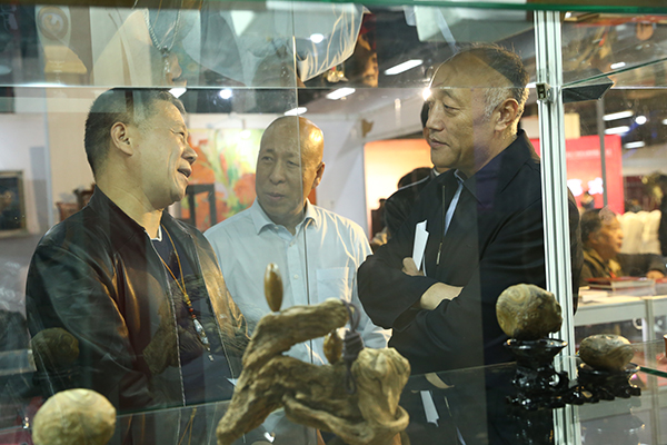 中国收藏家协会事业发展部主任李祥（中）为北京市文物局文物市场管理处处长哈骏（右）介绍藏品