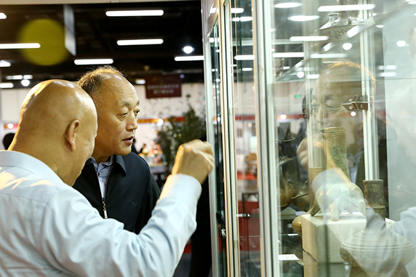 中国收藏家协会事业发展部主任李祥（左）为北京市文物局文物市场管理处处长哈骏（右）介绍藏品